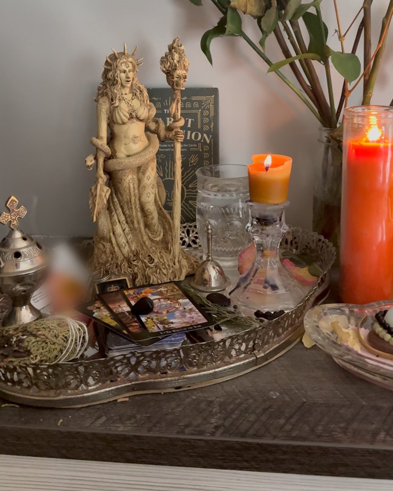 Hannah's altar with a goddess statue, candles, tarot cards and dried roses