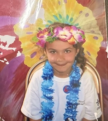Hannah as a little girl in a flower crown and blue lei