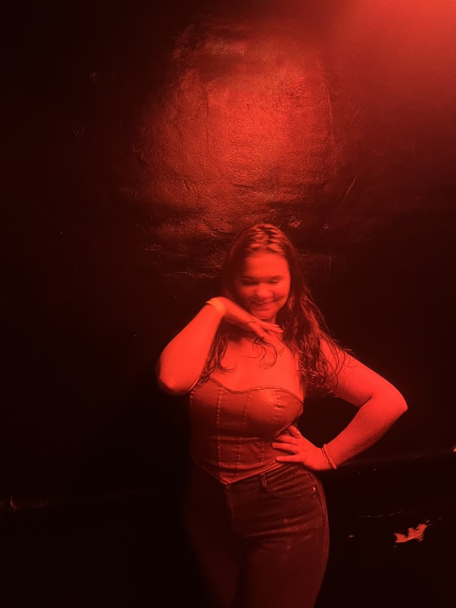 Hannah posing under red light, hand on her hip