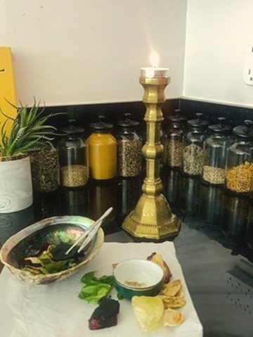 A brass candlestick and ritual herbs on a kitchen altar