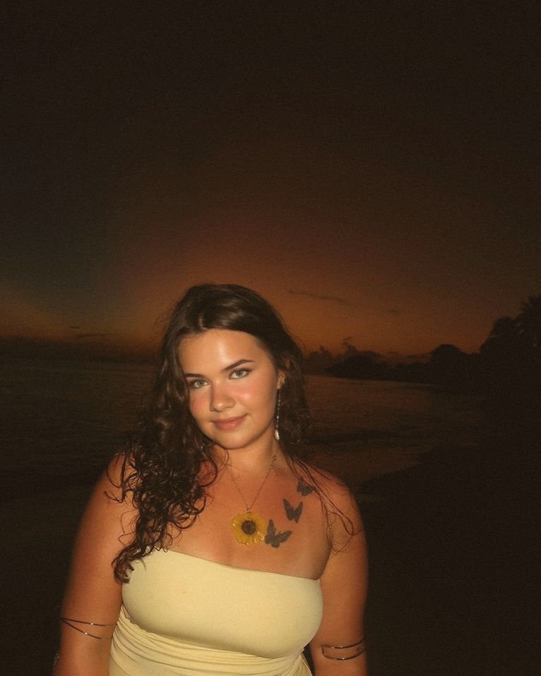 Hannah at sunset by the sea, wearing a sunflower necklace